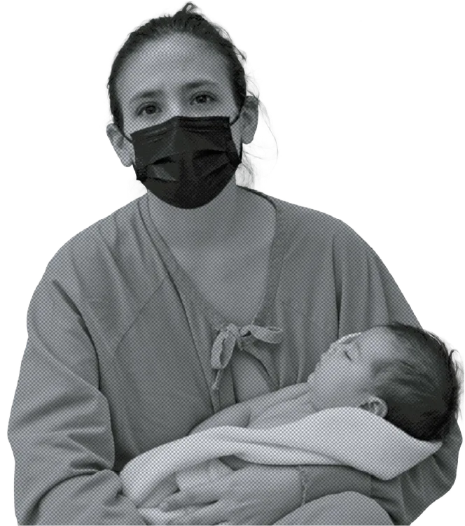 A mother wearing a face mask holds her newborn baby